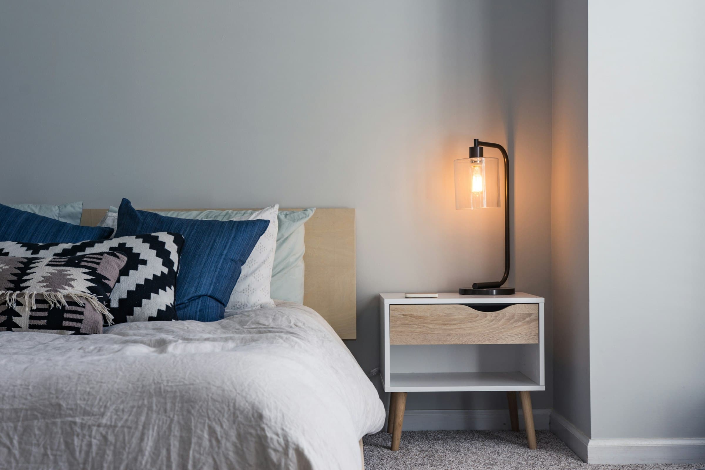 Spare guest room with white linen, wood floor, and morning light